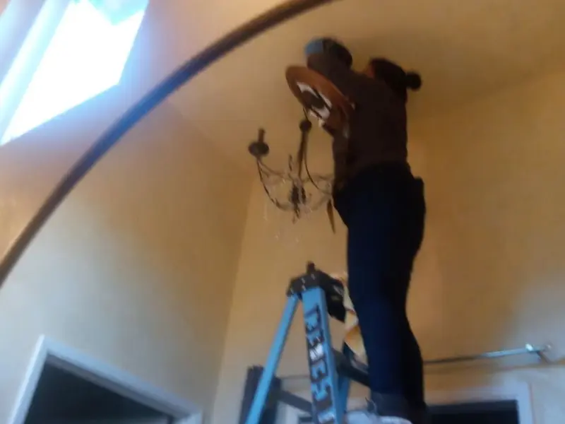 Electrician installing a chandelier in a Moravia residence